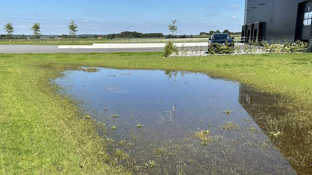 Grote plas water in een wadi op een grasveld naast een gebouw