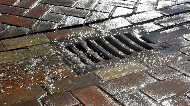 Regenwater stroomt richting de straatgoot