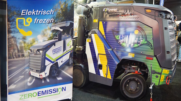 Promotional poster and a colorful electric-powered truck on display, emphasizing zero-emission messaging.