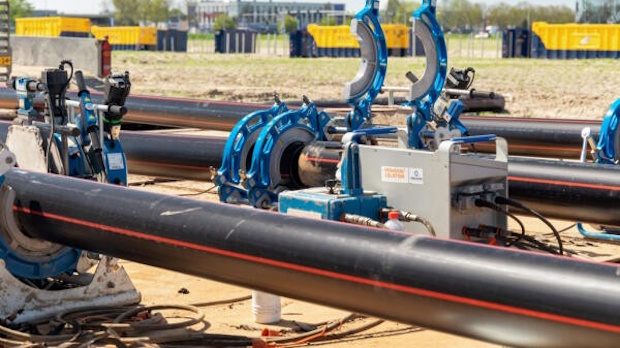 Industrial pipeline with blue clamp valves and support equipment at a construction site.